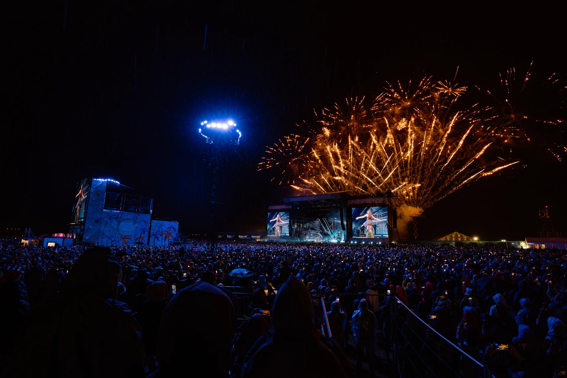 Widok na scenę główną festiwalu Opener 2024 w nocy, ze spektakularnymi fajerwerkami rozświetlającymi niebo nad publicznością.