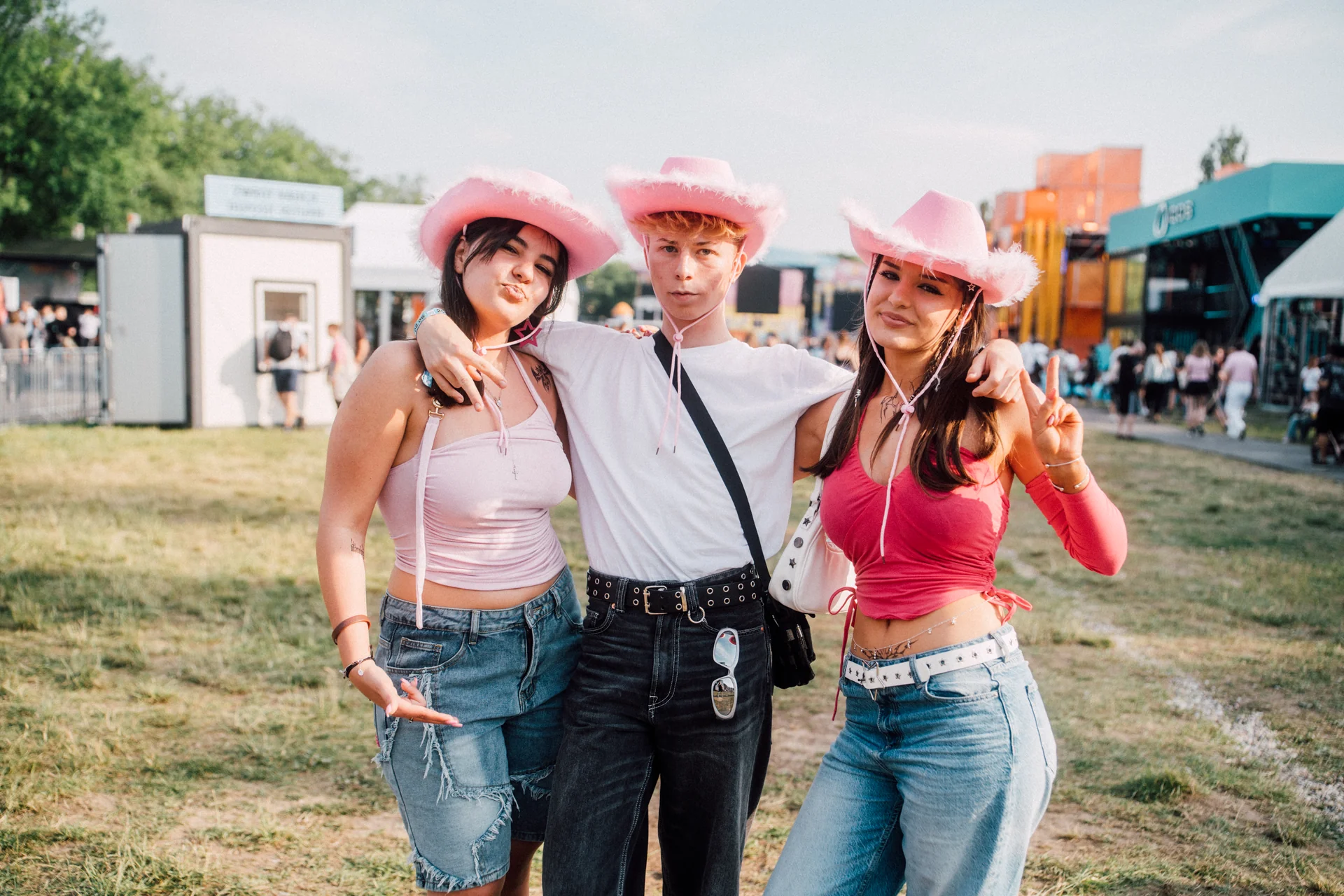Trójka młodych fanów w różowych kapeluszach kowbojskich, pozująca w festiwalowej modzie na Orange Warsaw Festival 2024.