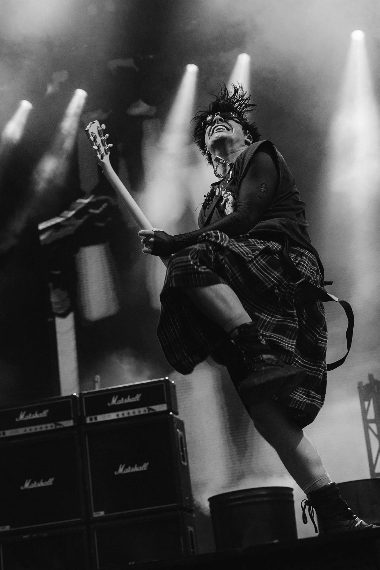 Czarno-białe zdjęcie Yungbluda skaczącego z gitarą na scenie Orange Warsaw Festival 2024, z mikrofonami Marshall w tle.