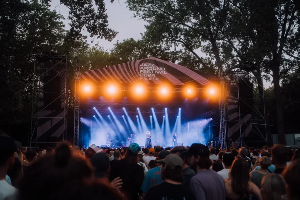 Szeroki kadr sceny Park Stage na Jazz Around Festival 2024, z zespołem występującym przed publicznością w świetle dziennym, z oświetleniem scenicznym.